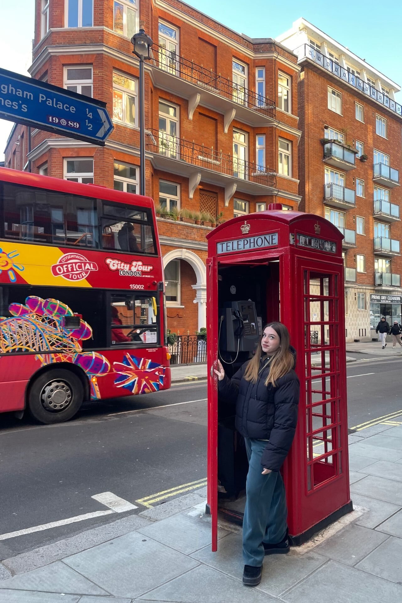Tαξίδι στο Λονδίνο: αξιοθέατα, γειτονιές, φαγητό, ψώνια Κορίτσι μέσα σε αγγλικό τηλεφωνικό θάλαμο με ένα κόκκινο λεωφορείο από πίσω της 